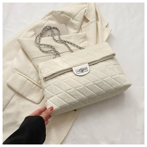Detail of white quilted handbag featuring silver metallic twist lock and chain strap