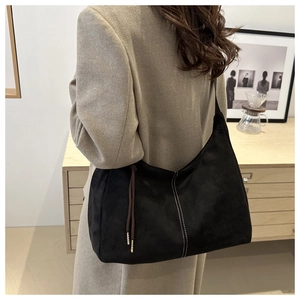 Detail of black suede tote bag featuring white contrast stitching and side drawstring