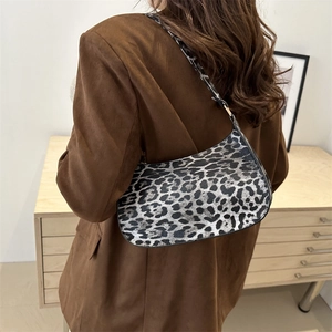Stylish leopard print baguette bag with black straps worn by a model in a brown blazer