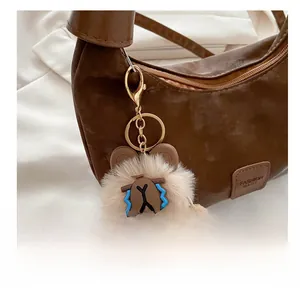 Close-up of a cute plush bear charm with blue tear details and golden metal carabiner