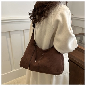 Detail view of brown matte hobo bag featuring white topstitching and tassel drawstring