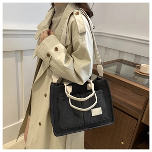 Detail of grey canvas tote bag with off-white handles and adjustable wide strap