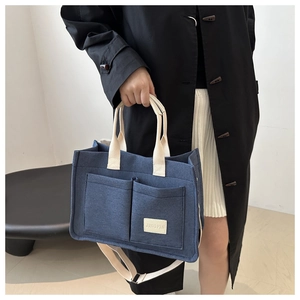 Detail of navy blue canvas tote bag showing front pockets and white brand label