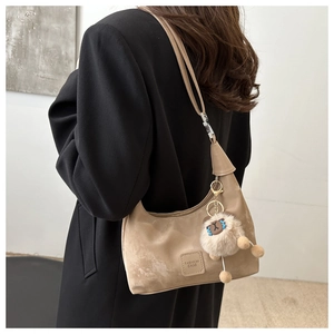 Detail of khaki hobo bag with fashion logo patch and cute plush animal keychain charm