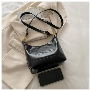 Close-up of black retro PU leather tote featuring embossed logo and gold metal hardware