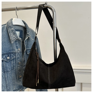 Dettaglio borsa tote in pelle scamosciata nera con cuciture bianche e pendente con nappe