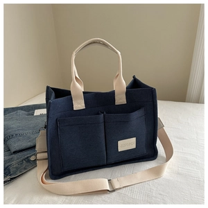 Large dark blue canvas tote bag with off-white handles and adjustable shoulder strap