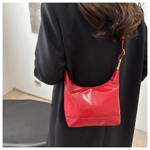 Detail of red oil-wax leather hobo bag with embossed logo and golden metal buckle