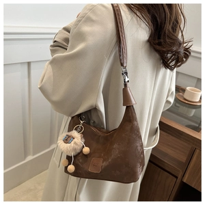 Detail of dark brown pleated hobo bag with vintage texture and plush sheep charm