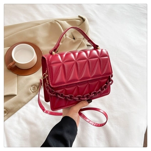 Détail d'un sac à main rouge matelassé avec chaîne dorée chic et bandoulière réglable