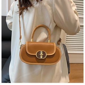 Dettaglio della chiusura in metallo vintage su borsa in pelle marrone con manico