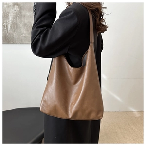 Macro shot of brown PU leather tote bag texture with wide shoulder strap on model
