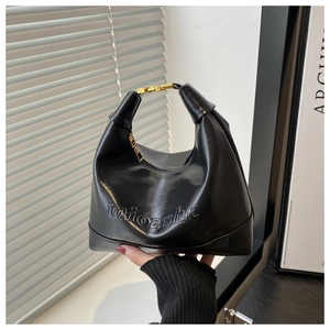 Detail shot of black faux leather hobo bag featuring mioashe embossed logo and gold hardware