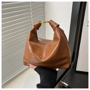 Detail of caramel brown PU leather hobo bag with gold metal buckle and embossed logo