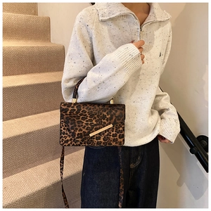 Detail of leopard print crossbody bag featuring a gold metal bar and textured finish