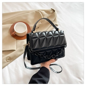 Détail du petit sac carré noir matelassé avec chaîne texturée et rabat élégant