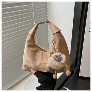 Detail of khaki suede half-moon underarm bag with metal buckle and plush lion charm