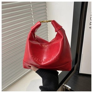 Detailed view of red crescent tote bag featuring golden metal buckles and embossed logo