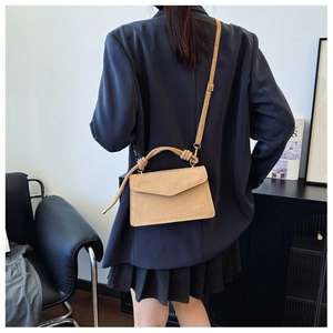 Detail view of khaki matte crossbody bag featuring unique knotted top handle and flap cover