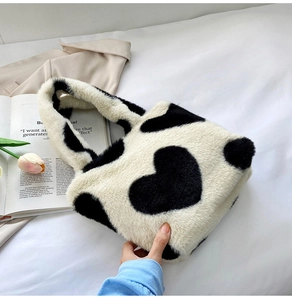 Dettaglio di una borsa tote in peluche color crema con motivo a cuore nero stampato