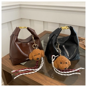 Detailed close-up of high-gloss faux leather tote bags with metal buckles and teddy charms