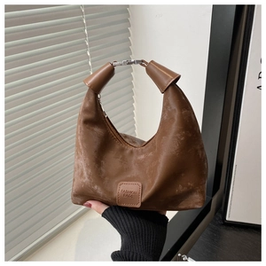 Detail of vintage brown suede dumpling bag with rolled handle and metal buckle
