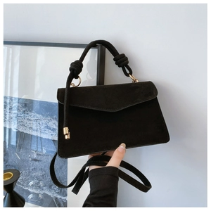 Detail einer minimalistischen mattschwarzen Tasche mit Knotengriff und Golddekor
