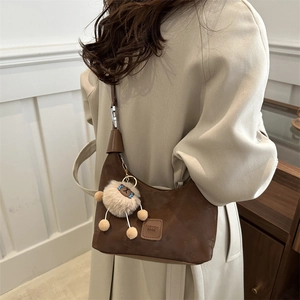 Brown frosted leather crescent shoulder bag with pleated detail and cute plush pendant charm