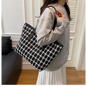 Detail of checkered tote bag made of tweed material with black leather shoulder straps