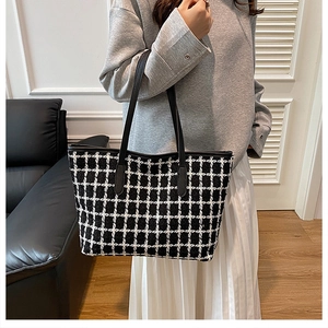 Detail of checkered tweed tote bag with black leather handles on a model shoulder