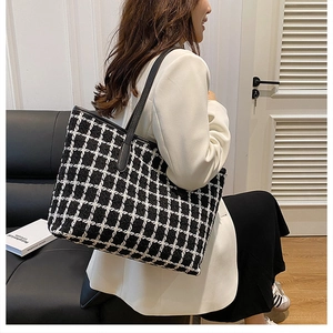 Close-up of contrast checkered tote bag with black leather straps and premium wool texture