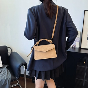 Matte khakifarbene Umhängetasche mit Knotengriff und Klappe, am Model als Crossbody gezeigt