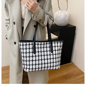 Close-up of black and white plaid woven tote bag with tweed texture and leather strap