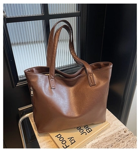 Close-up of brown faux leather tote bag showing side zipper and refined texture