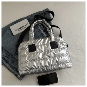 Detail of silver metallic puffer tote bag with quilted nylon and black straps
