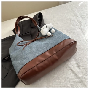 Dettaglio della borsa tote in denim e pelle con ciondolo a nuvola e fiocco decorativo