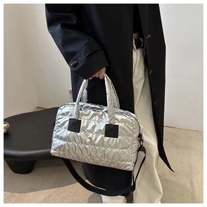 Detail of silver quilted puffer bag with glossy finish and detachable black nylon shoulder strap