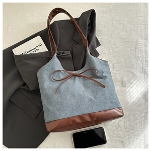 Dettaglio borsa tote in denim con finiture in pelle e fiocco marrone stile ufficio
