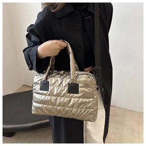 Detail of champagne gold quilted tote bag with black strap and metallic puffer texture