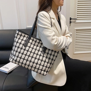Large black and white checkered tweed tote bag with leather handles shown with model