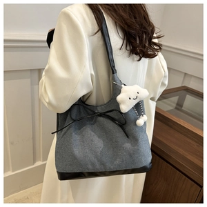 Dettaglio della borsa tote in denim con ciondolo a nuvola di peluche e fiocco a spalla