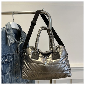 Detail of silver metallic quilted tote bag with padded handles and adjustable black strap