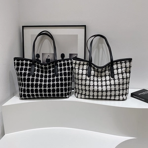Contrast checkered knit tote bags in black and white with leather straps on a modern stand