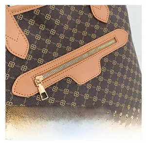 Detailed macro view of gold-tone metal zipper and monogram canvas on a tote bag