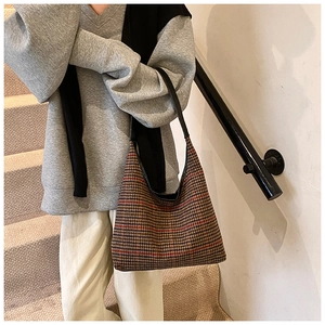 Close-up of vintage plaid tote bag with red and brown pattern on model's shoulder