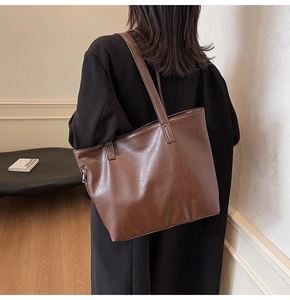 Macro detail of large dark brown leather tote bag showing side zipper and rich texture