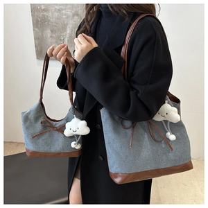 Dettaglio di borse tote in denim grigio con finiture in pelle marrone e charm a nuvola
