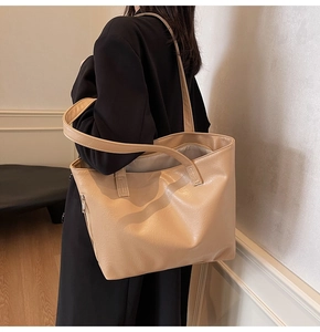 Close-up of a large beige tote bag with soft leather texture and long shoulder straps