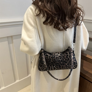Sac à bandoulière léopard minimaliste porté par un mannequin sur un long manteau blanc