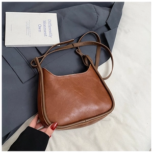 Detail of retro brown leather shoulder bag with curved top and fine textured finish